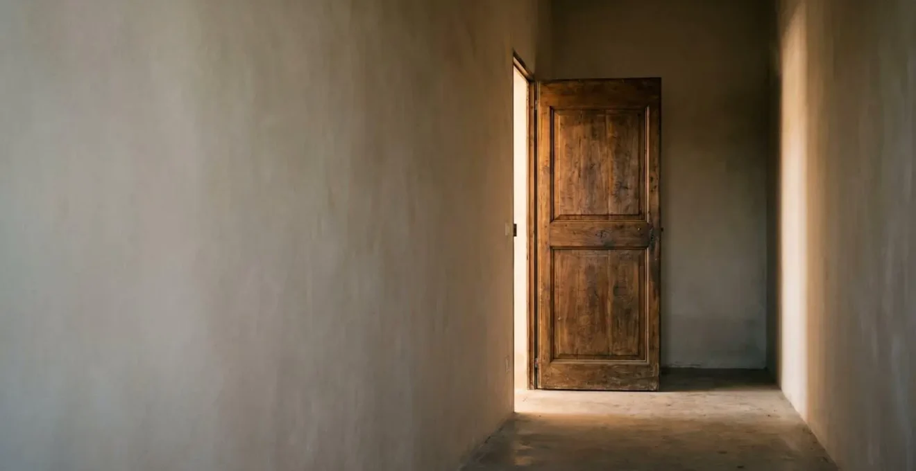 Porte en bois entrouverte laissant filtrer une lumière douce dans un couloir sombre, symbolisant une issue juridique face à un blocage personnel